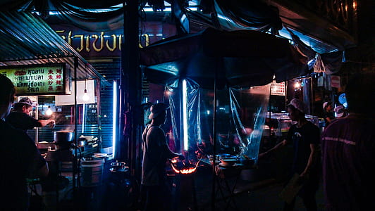 man standing infront of man cooking beside store thumbnail