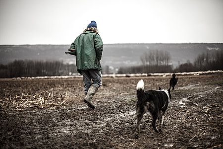 man walking on brown soil near black dog at daytime thumbnail