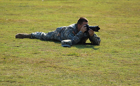 Military Crouching on Green Grass Using Dslr Camera during Daytime thumbnail