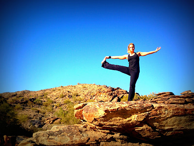 woman wearing black tank top and pants standing on rock formation under clear blue sky thumbnail