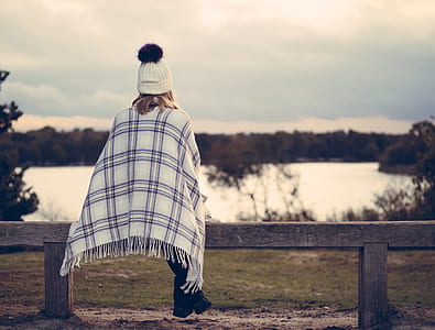 person sitting on brown wooden bench nearby calm body of water thumbnail