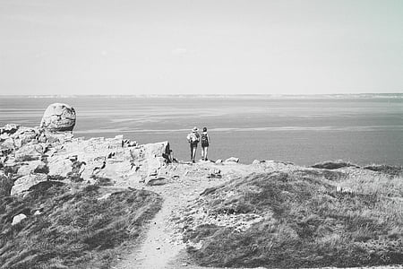 grayscale photo of two person standing towards sea thumbnail