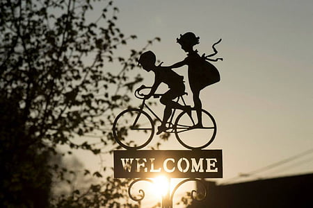 silhouette of two children on bike with welcome sign thumbnail
