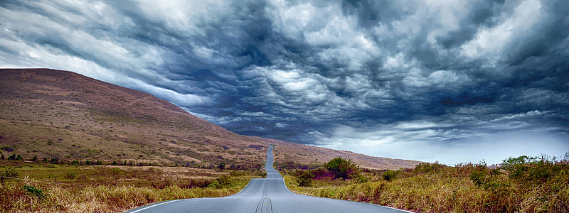 concrete road towards mountain under gray sky thumbnail