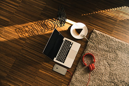 MacBook Pro beside sliced cake on plate with headphones and phone placed on floor thumbnail