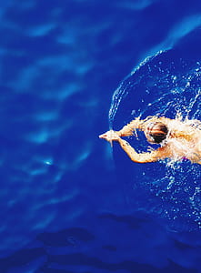 person swimming in blue water aerial photography thumbnail
