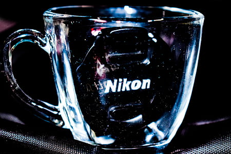 Close Up Photo Of Clear Glass Mug With Nikon Lens Cap thumbnail