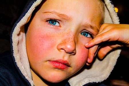 close-up photography of boy wearing black and white hooded jacket with hand leaning on face thumbnail