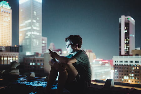 man wearing gray tee shirt sitting on rooftop during night time thumbnail
