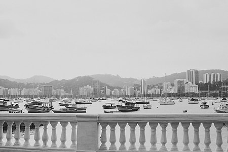 boats on body of water near building in greyscale photography thumbnail