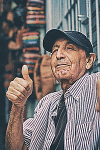 man wearing cap and pinstriped dress shirt doing thumbs up thumbnail