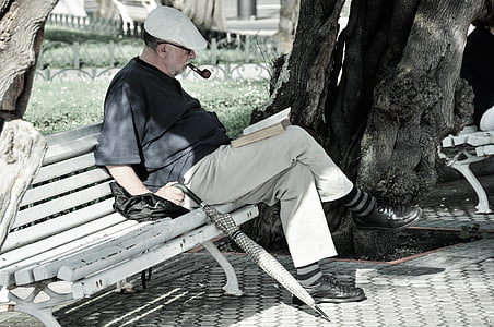 man in black shirt sitting on bench reading book thumbnail