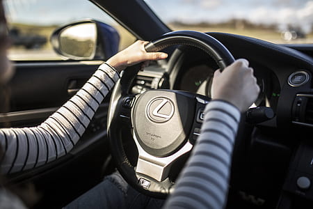 person holding on black Lexus car steering wheel thumbnail