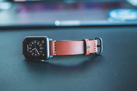 photo of space gray aluminum case Apple Watch with brown leather strap on black surface thumbnail