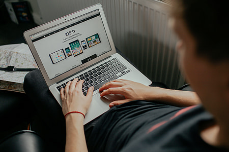 person using macbook reading about IOS 11 thumbnail