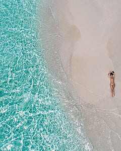 aerial photography of woman wearing gray bikini lying on seashore at daytime thumbnail
