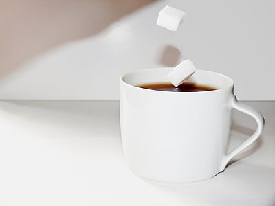 white ceramic teacup filled with black liquid and sugar cube thumbnail