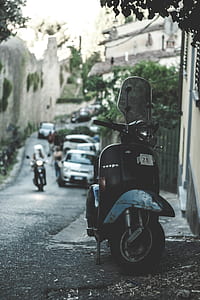 black motor scooter parked beside house thumbnail