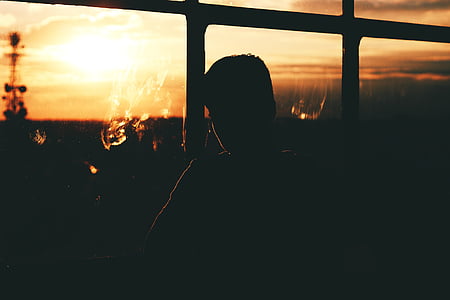 silhoutte photography of person standing beside window thumbnail