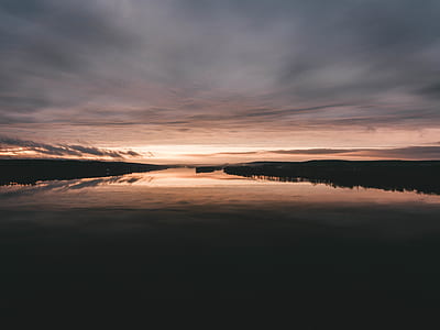 lake under gray cloudy sky at golden hour thumbnail
