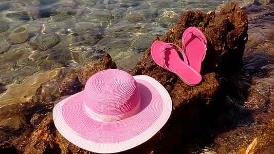 pink and white sun hat with sandals on rock thumbnail