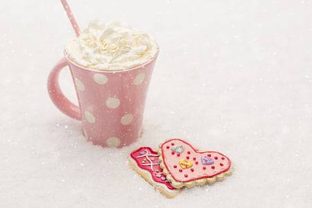 two heart shaped cookies beside whip cream served on white and pink polka dot mug thumbnail