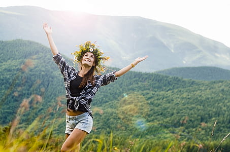 woman with flower headdress looking up with hand raised hands outdoor thumbnail