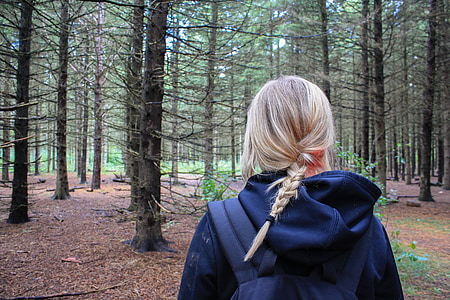 girl wearing blue hoodie standing near trees in the middle of the forest thumbnail