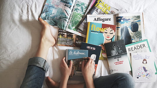 person sitting near pile of assorted-titled novel books thumbnail