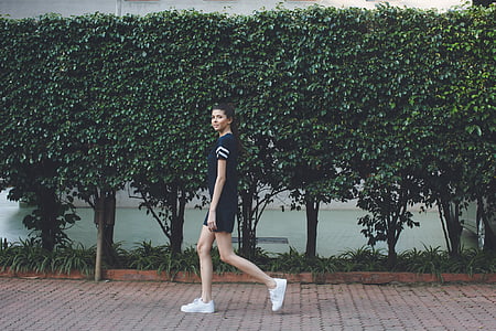 woman walking in pathway near green leafed trees thumbnail