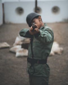 man pointing rifle in selective focus photography thumbnail