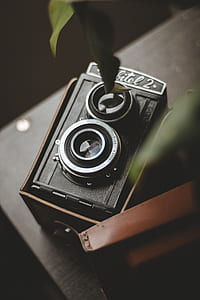 vintage black and gray camera inside case on brown wooden table selective focus photography thumbnail