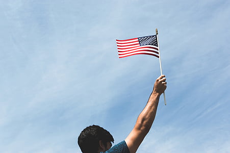 man holding US flag during daytime thumbnail