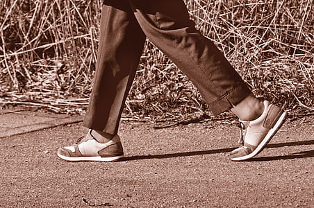 person walking beside grass field during daytime thumbnail