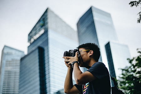 selective focus photo of man wearing black taking photo using black DSLR camera thumbnail
