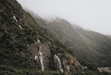 waterfall on mountain under foggy sky thumbnail