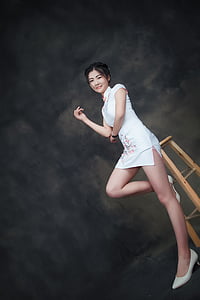 woman in white cheongsam sitting on stool thumbnail