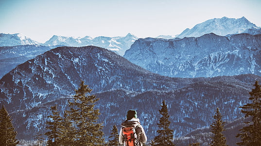 person standing near trees with mountain at distance during daytime thumbnail