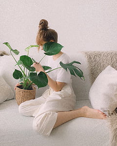 Woman Wearing White Crew-neck Shirt and White Pants While Sitting on White Couch thumbnail