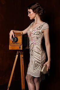woman in gray and brown paisley scoop-neck dress standing near brown camera thumbnail