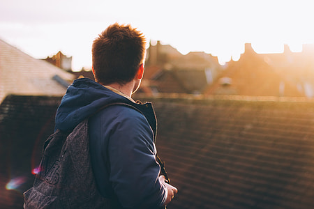 man wearing blue jacket with brown backpack thumbnail