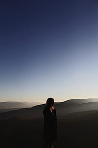 selective focus photography of woman on mountain cliff thumbnail