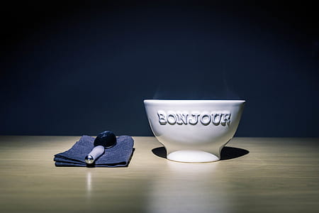 Bonjour Embossed White Ceramic Bowl on Table Beside Stainless Steel Spoon on Black Table Textile thumbnail