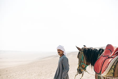man standing beside horse thumbnail