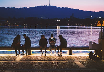 five person sitting on a bench beside body of water thumbnail