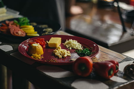 diced cheeses on round maroon ceramic plate on top of table thumbnail