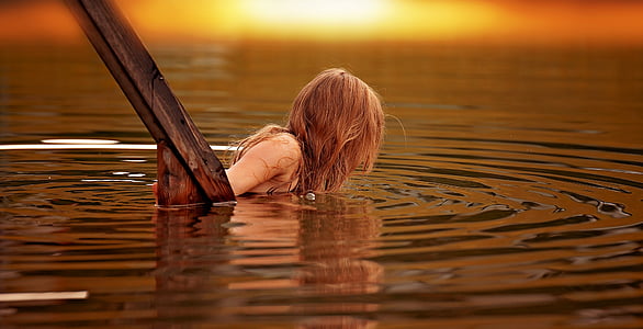 blonde haired woman on water near wood thumbnail