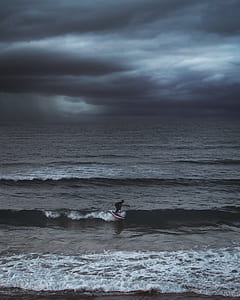 person using black surfboard on sea waves thumbnail