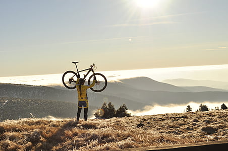 person lifting bike near bush during daytime thumbnail