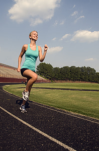 women in blue tank top running on track field during daytime thumbnail